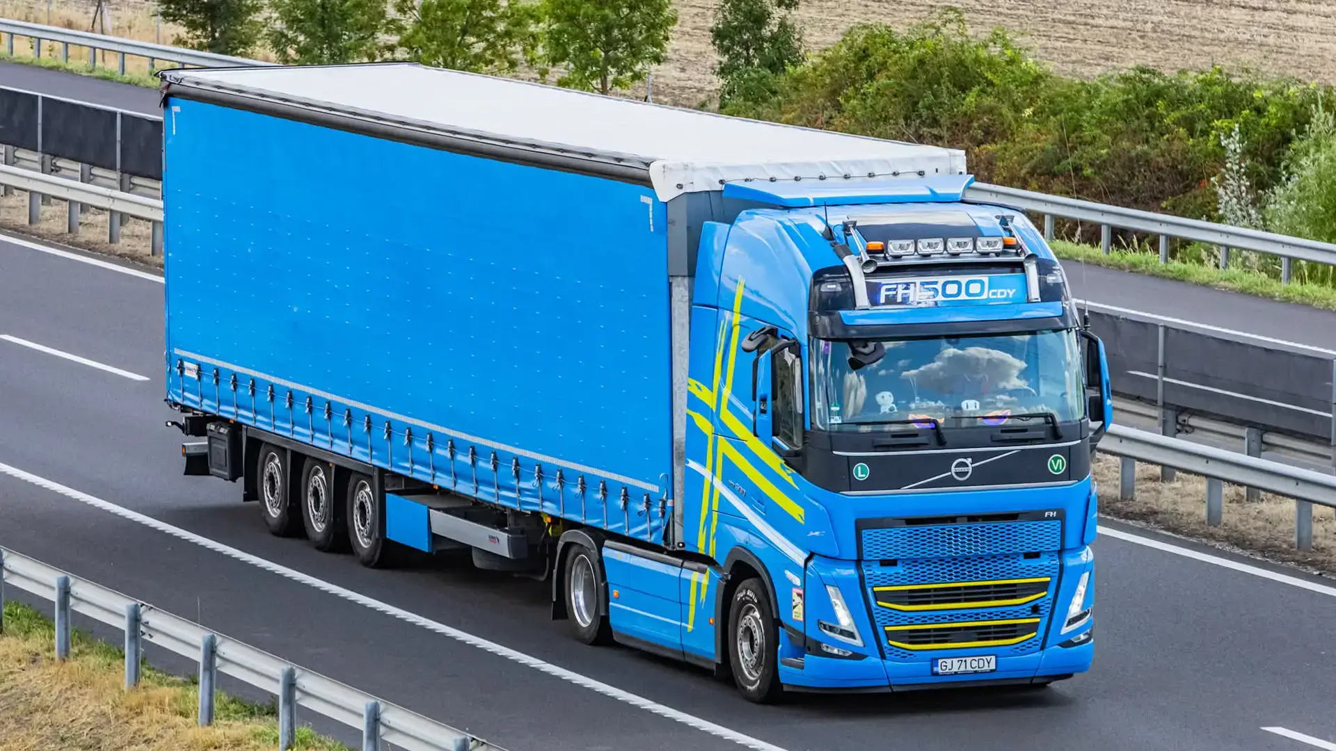 Camion Volvo modern si semiremorca mega cu prelata fotografiat pe autostrada